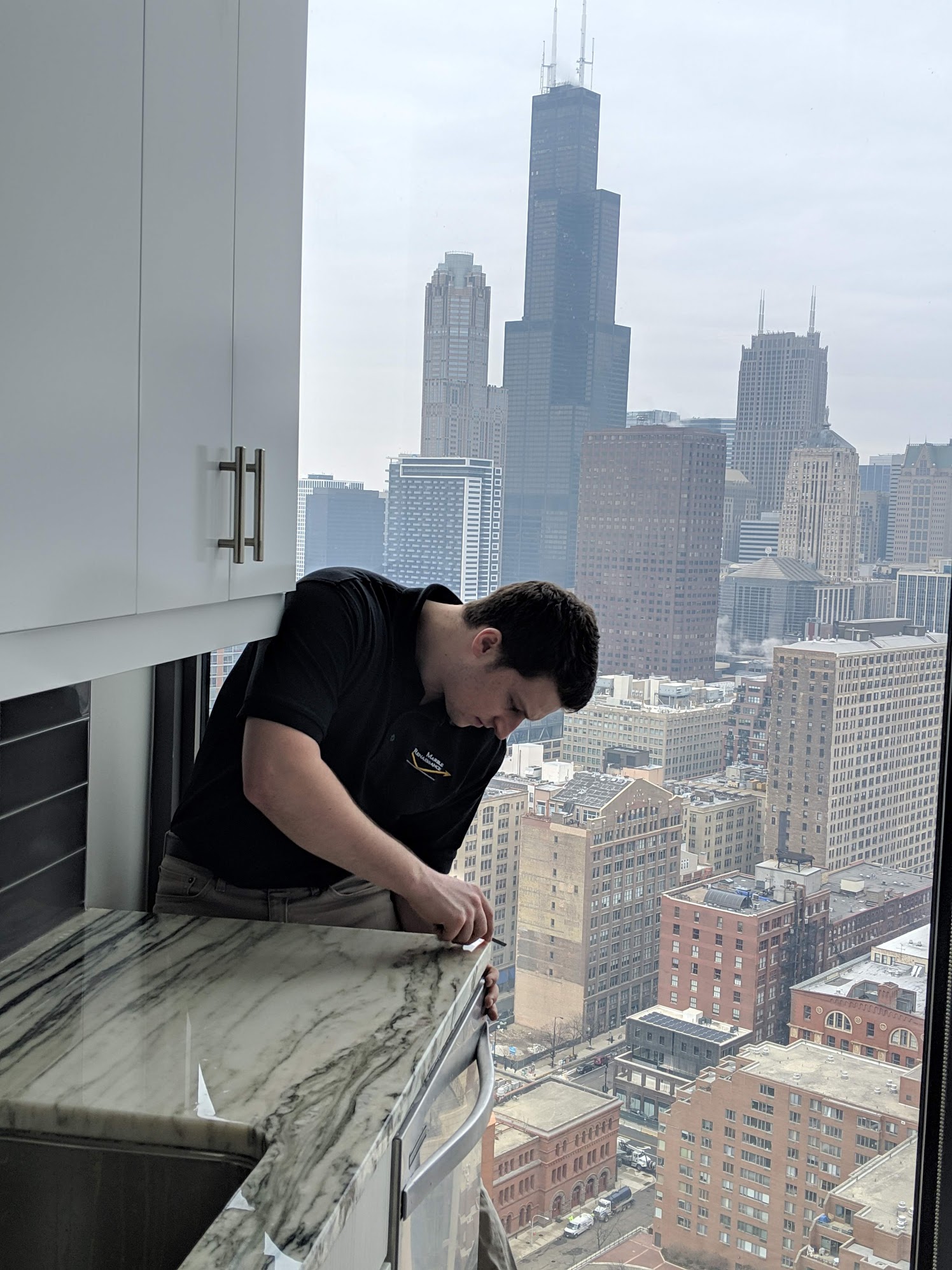 Marble Renaissance employee installing TuffSkin on Marble countertop in high-rise with Willis Tower in the background